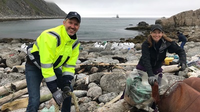 Mann og kvinne rydder søppel på en strand ved Nordkapp.